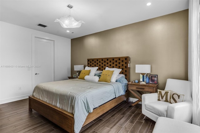 bedroom with dark wood-type flooring and an inviting chandelier