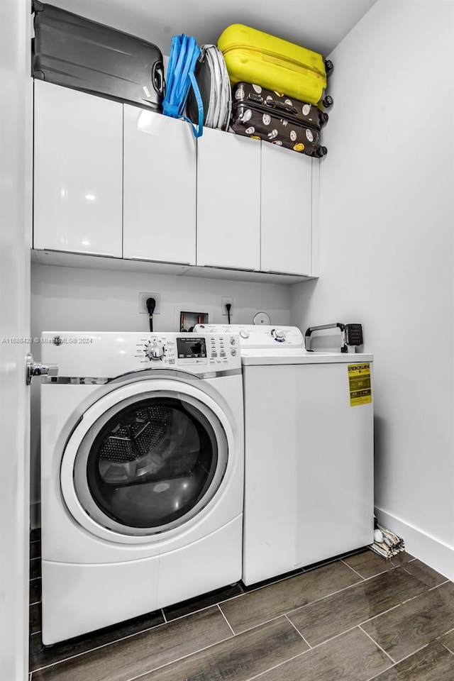 clothes washing area featuring cabinets, dark wood-type flooring, and washing machine and dryer