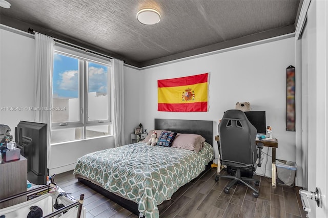 bedroom featuring a textured ceiling and dark hardwood / wood-style floors