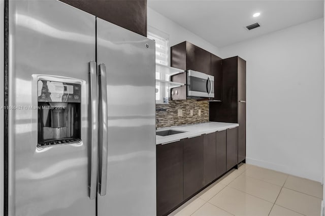 kitchen featuring decorative backsplash, appliances with stainless steel finishes, dark brown cabinetry, and light tile patterned floors