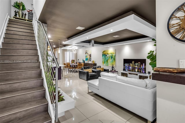 tiled living room with a chandelier and a tray ceiling