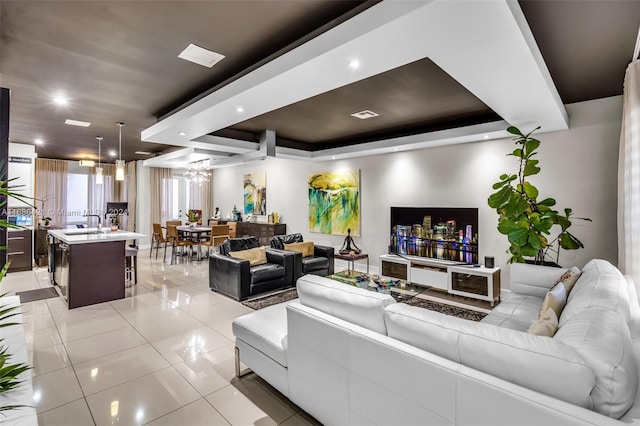 tiled living room featuring a raised ceiling and a chandelier