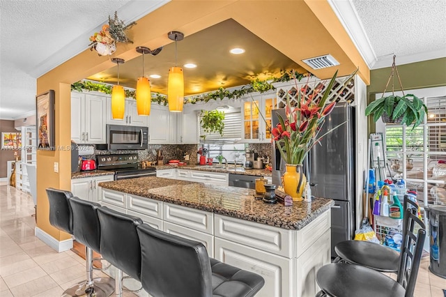 kitchen featuring white cabinets, light tile patterned flooring, pendant lighting, appliances with stainless steel finishes, and a textured ceiling