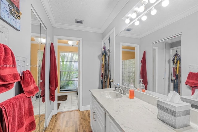 bathroom with vanity, ornamental molding, hardwood / wood-style flooring, and a textured ceiling