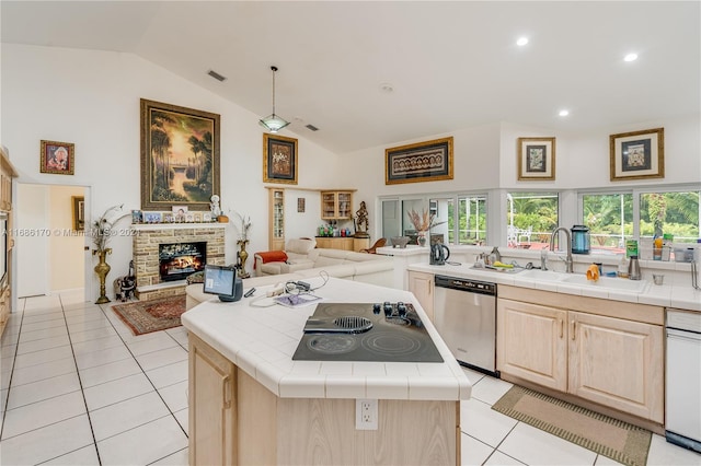 kitchen featuring tile countertops, vaulted ceiling, stainless steel dishwasher, and a center island