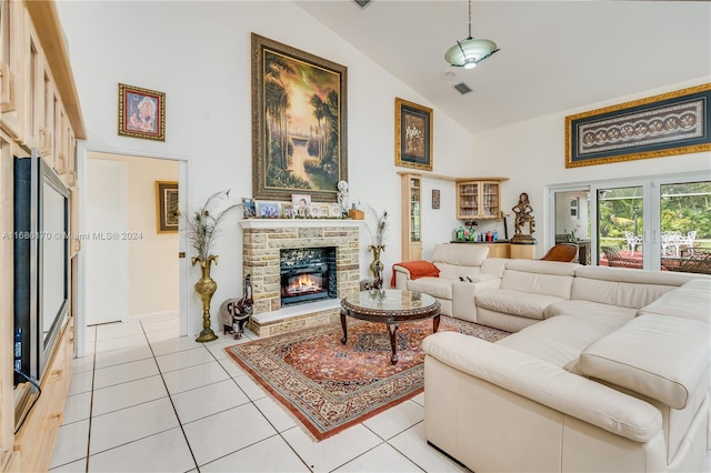 living room featuring a stone fireplace, light tile patterned flooring, and high vaulted ceiling