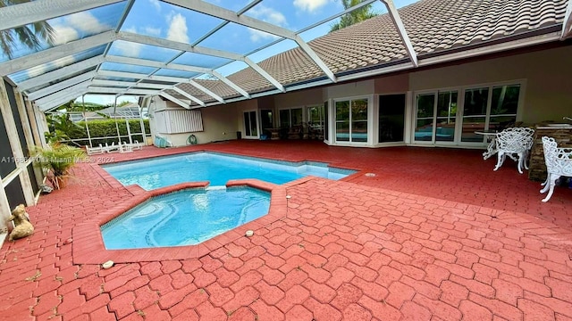 view of pool featuring an in ground hot tub, a patio, and glass enclosure