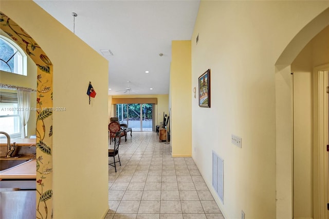 hall featuring light tile patterned flooring, a high ceiling, and a wealth of natural light