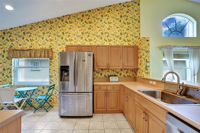 kitchen featuring appliances with stainless steel finishes, light tile patterned floors, lofted ceiling, and sink