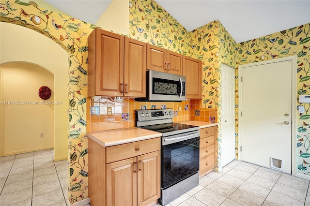 kitchen featuring backsplash, light tile patterned floors, and stainless steel appliances