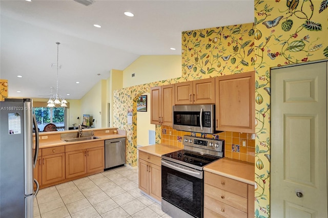 kitchen featuring sink, hanging light fixtures, a notable chandelier, vaulted ceiling, and appliances with stainless steel finishes