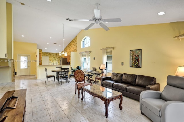 living room with ceiling fan with notable chandelier, high vaulted ceiling, and light tile patterned flooring