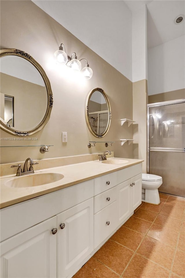 bathroom featuring tile patterned floors, vanity, toilet, and a shower with shower door