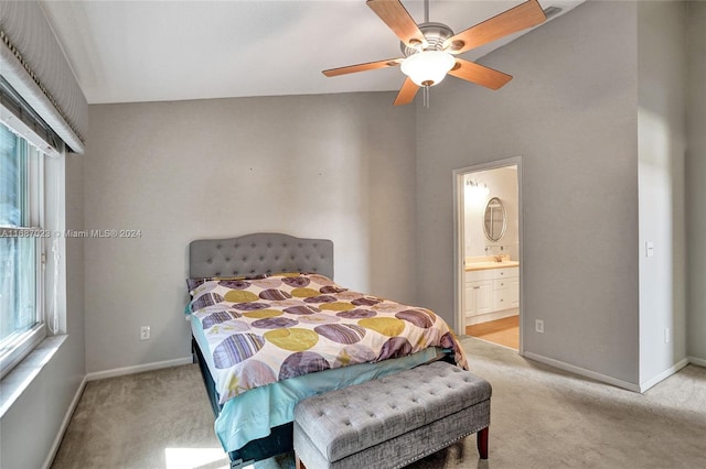 bedroom featuring light carpet, ensuite bathroom, vaulted ceiling, and ceiling fan