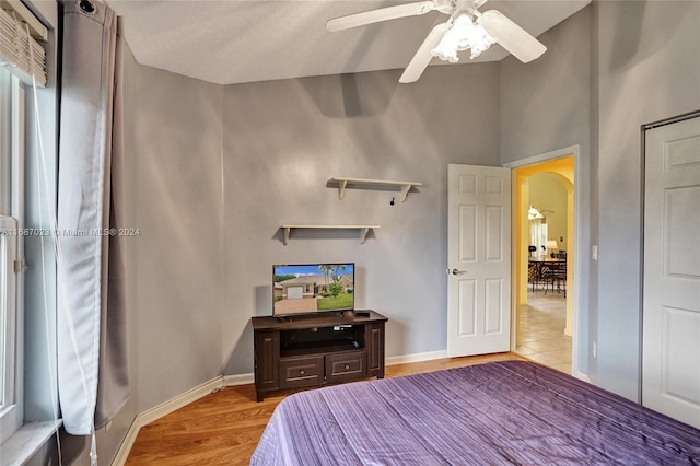 bedroom featuring lofted ceiling, ceiling fan, light hardwood / wood-style flooring, and a textured ceiling