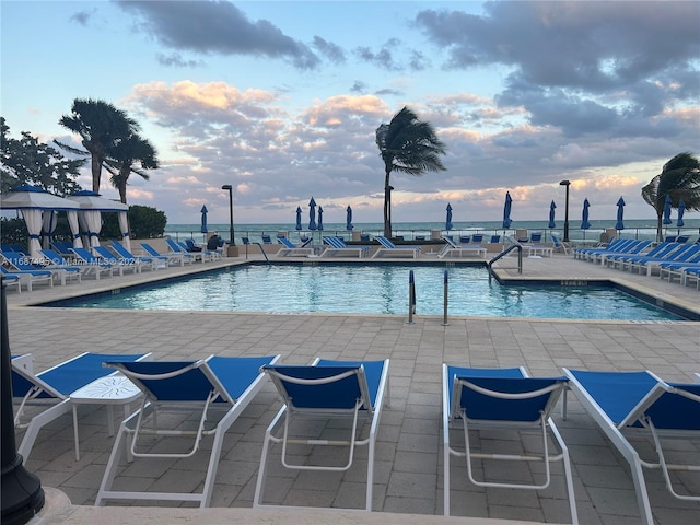 pool at dusk featuring a patio area