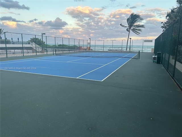 view of tennis court with a water view