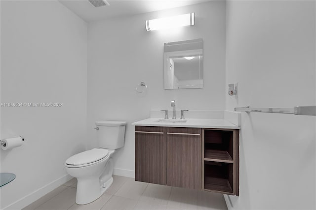 bathroom with toilet, vanity, and tile patterned floors