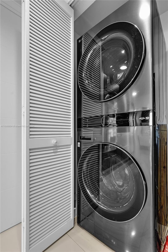 laundry area with light tile patterned floors and stacked washer and dryer