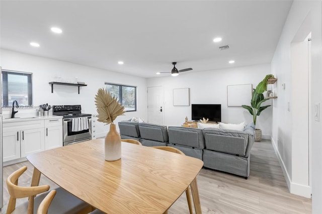 dining room featuring sink, light wood-type flooring, and ceiling fan