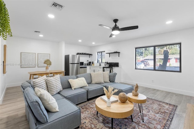 living room with sink, light hardwood / wood-style floors, and ceiling fan