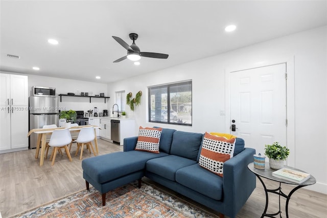 living room featuring light hardwood / wood-style floors, sink, and ceiling fan