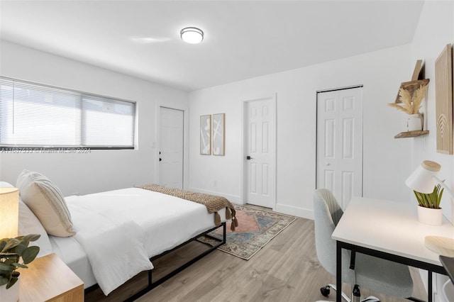 bedroom with two closets and light hardwood / wood-style floors