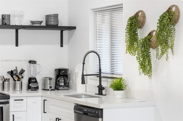 kitchen with white cabinetry, dishwasher, sink, and light stone counters