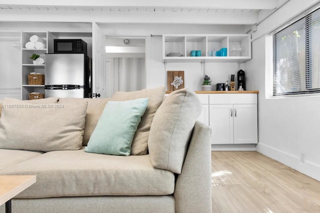 living room featuring light hardwood / wood-style floors, beam ceiling, and wooden ceiling