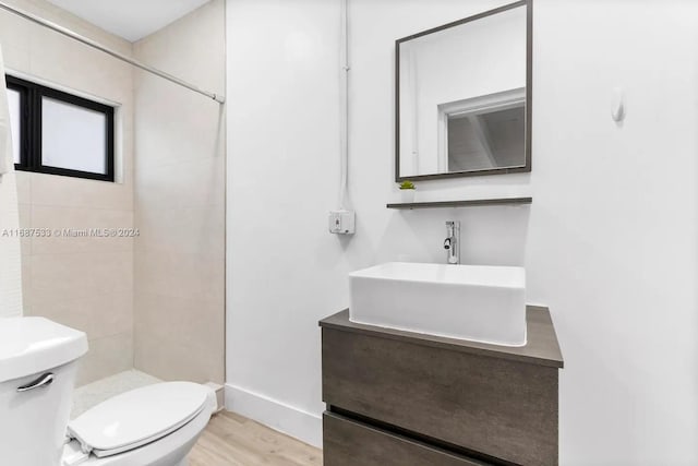 bathroom featuring vanity, toilet, hardwood / wood-style flooring, and tiled shower