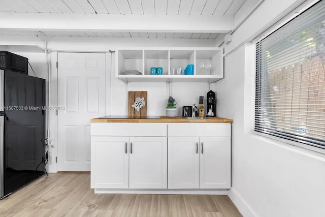 bar with butcher block countertops, white cabinetry, light hardwood / wood-style floors, beamed ceiling, and black refrigerator