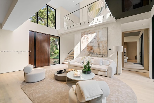 living room featuring a high ceiling, light wood-type flooring, and a healthy amount of sunlight