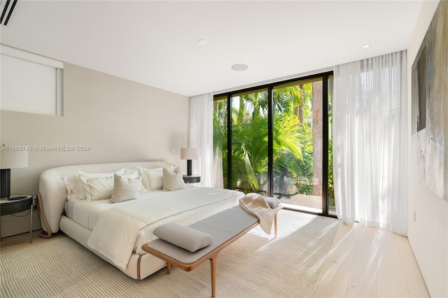 bedroom with floor to ceiling windows, light wood-type flooring, and multiple windows