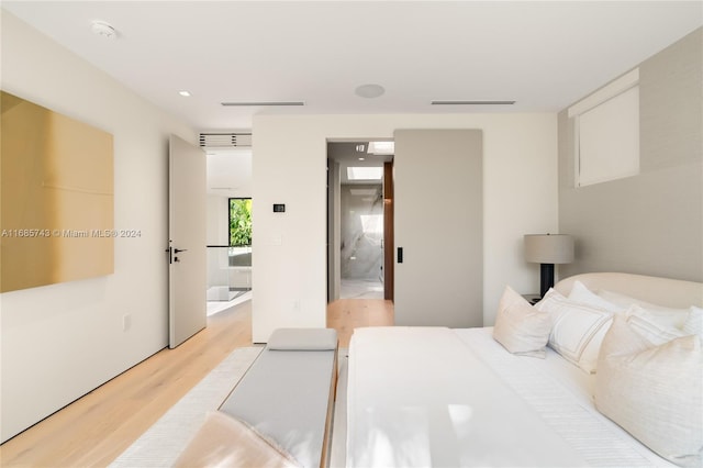 bedroom with connected bathroom and light hardwood / wood-style flooring