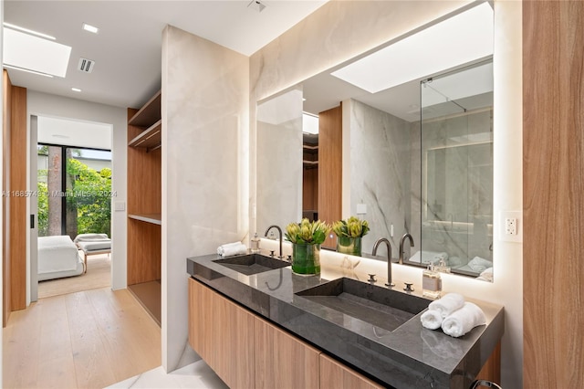 bathroom with walk in shower, a skylight, vanity, and hardwood / wood-style flooring