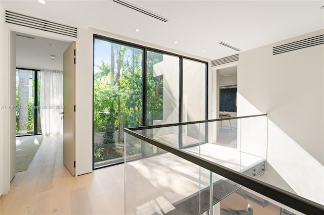 corridor featuring a wall of windows and light wood-type flooring