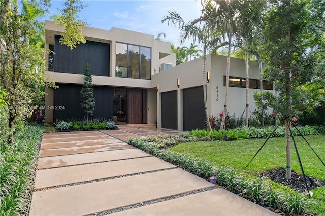 contemporary home featuring a garage and a front lawn