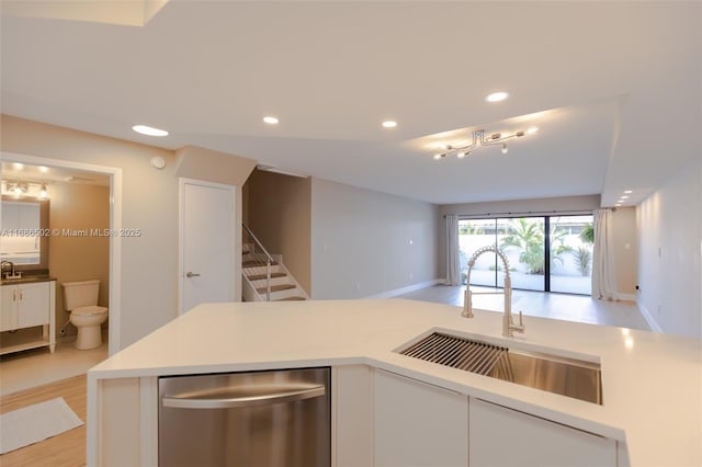 kitchen featuring dishwasher, light countertops, a sink, and white cabinetry