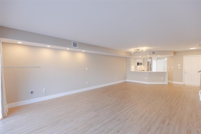 unfurnished living room with light wood-type flooring, baseboards, visible vents, and recessed lighting