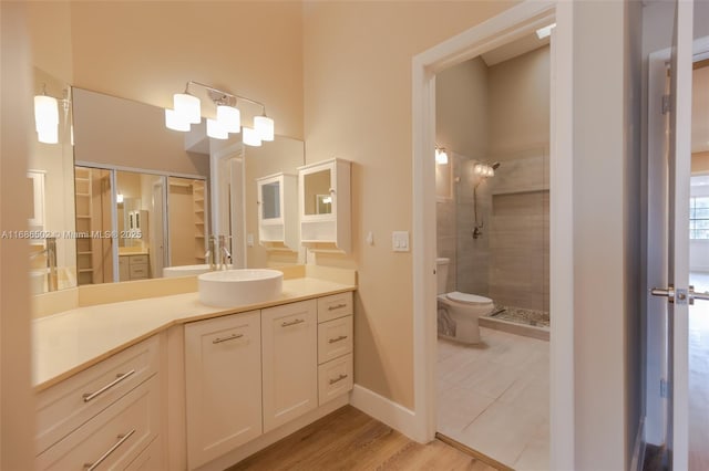 full bath featuring baseboards, toilet, wood finished floors, vanity, and a shower stall