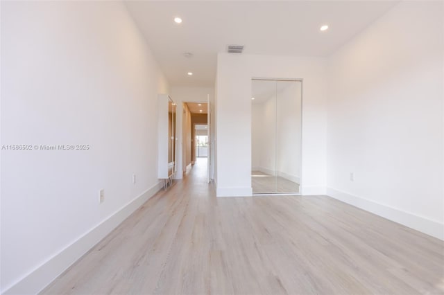 empty room with light wood-type flooring, visible vents, baseboards, and recessed lighting