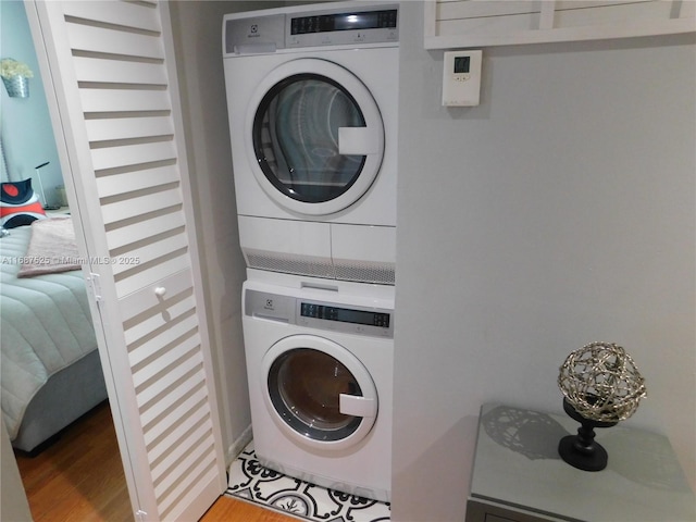 laundry area with laundry area, wood finished floors, and stacked washer and clothes dryer