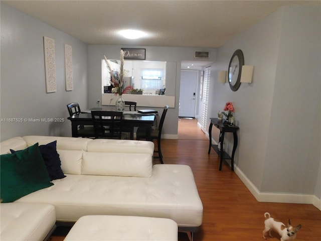 living room featuring visible vents, baseboards, and wood finished floors