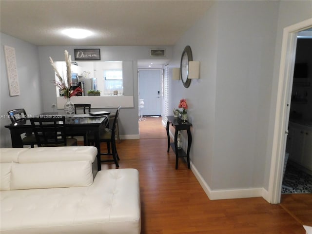 living room featuring wood finished floors, visible vents, and baseboards