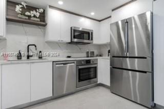 kitchen featuring backsplash, sink, appliances with stainless steel finishes, and white cabinets