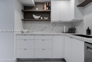 kitchen featuring white cabinetry, light stone counters, tasteful backsplash, and stainless steel dishwasher