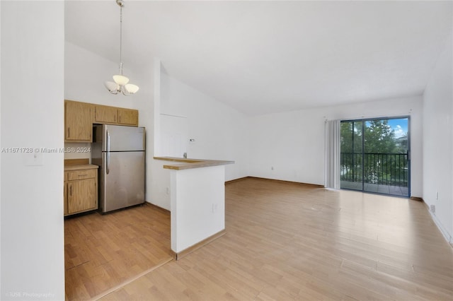 kitchen with stainless steel fridge, decorative light fixtures, an inviting chandelier, light hardwood / wood-style floors, and kitchen peninsula