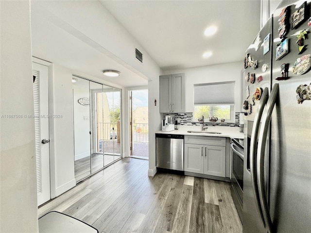 kitchen featuring light hardwood / wood-style floors, stainless steel appliances, sink, and gray cabinets