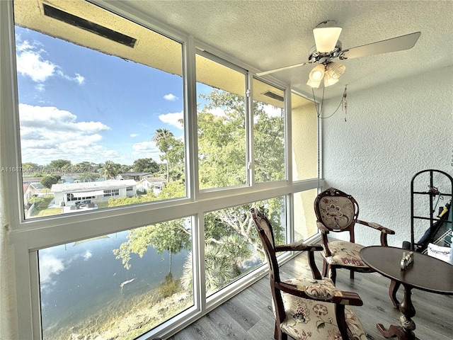 sunroom / solarium with a water view and ceiling fan