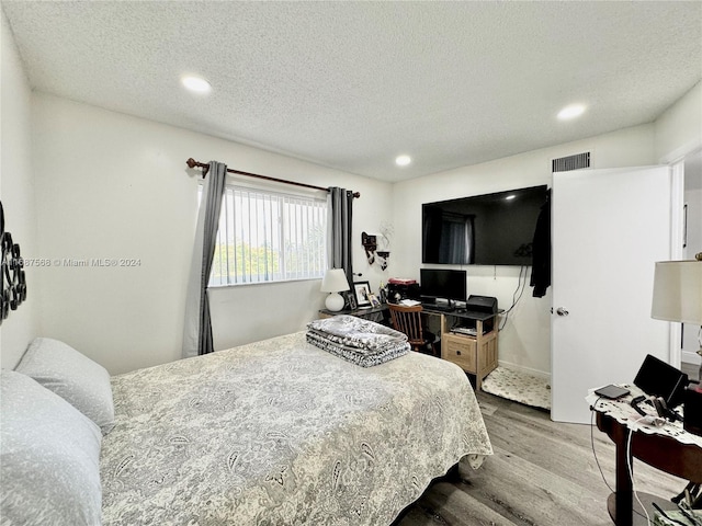 bedroom with a textured ceiling and hardwood / wood-style flooring